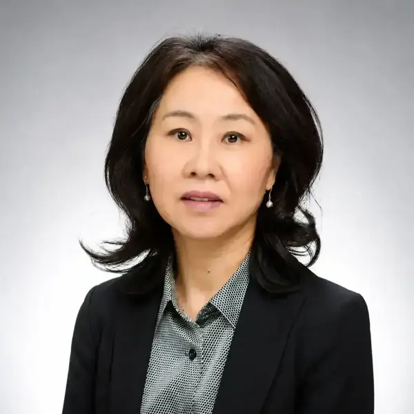 A woman with short hair wears black jacket and gray shirt.